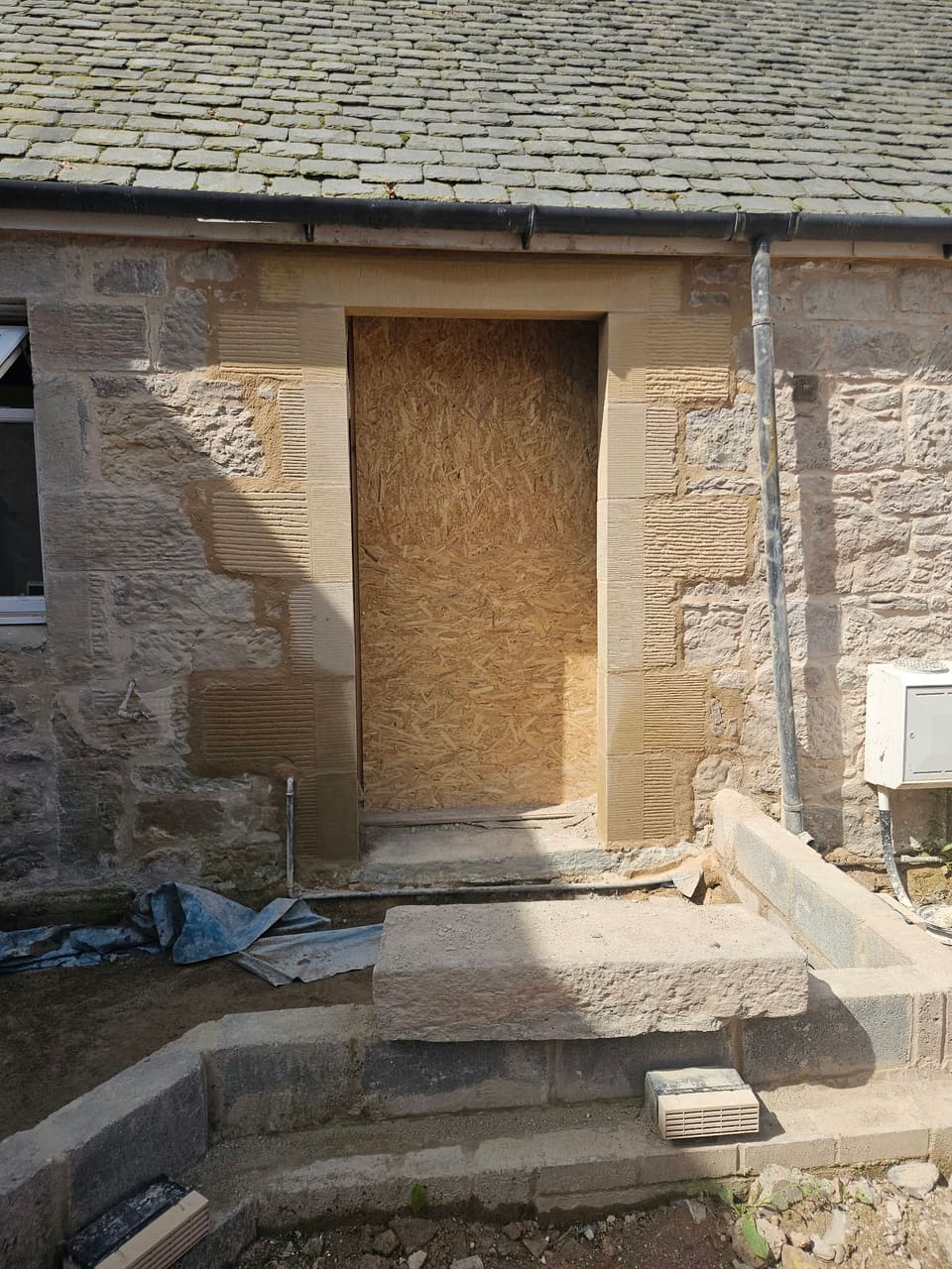 The front opening as a doorway, with new sandstone rybats and lintel built in and a large stone step below.