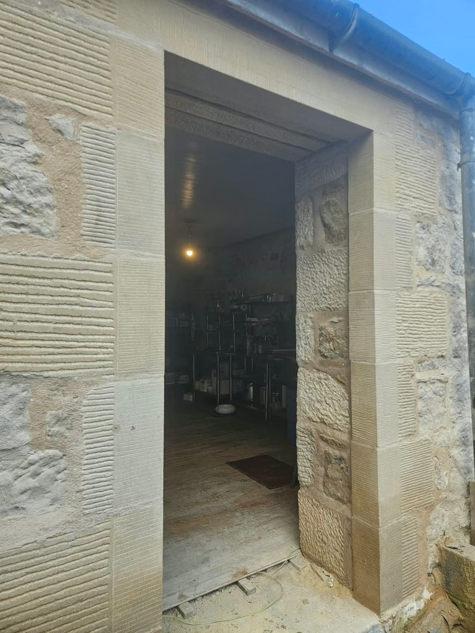 Open doorway with new sandstone rybats of alternating long and short stones, broached faces and tooled margins, under a new lintel.