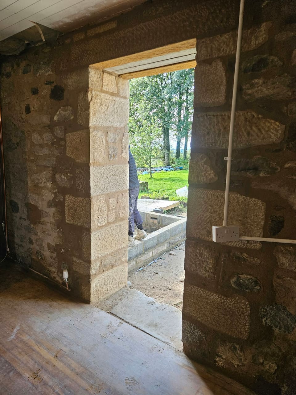 Inside view of the back doorway from an angle, dressed sandstone at the reveal, trees beyond.